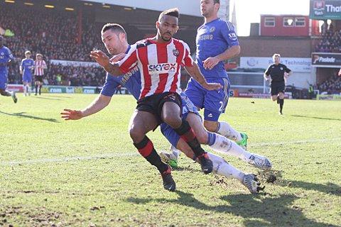 Tough day: Chelsea defender Gary Cahill clatters in to Brentford's Shaleum Logan in Sunday's 2-2 draw at Griffin Park
